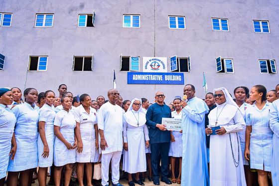 Peter Obi standing with nuns, nurses and students for a group photograph outside a college building