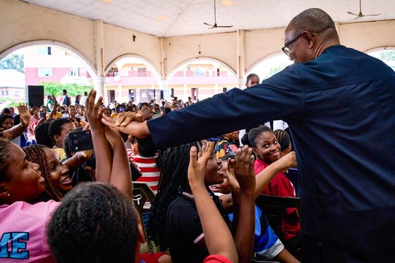 A packed hall of young people with phones and raised hands as Peter Obi reaches across to them