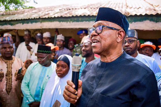 Peter Obi speaking into a microphone in a northern town, surrounded by men in caps and young women in hijabs